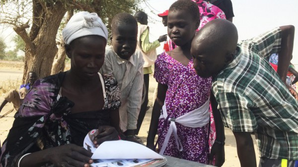 In search of their loved ones, a group of people in Leer review a book containing photos of South Sudanese children located in the neighbouring countries. CC BY-NC-ND/ICRC/Pawel Krzysiek