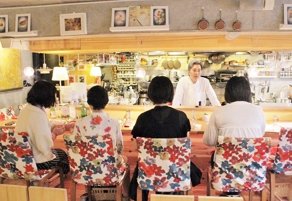 料理教室での参加者にメニューなどについて説明するシェフの荒田靖さん＝撮影・橋本正人