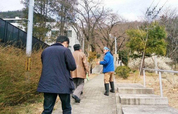 廃棄物を上から見ようと昇っていく関さんとツアー参加者の皆さん。左が仮置き場、右が花の咲く公園でした=撮影・松中みどり