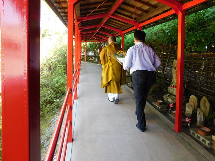 花束を持って那須与一の供養塔に向かう那須正美さん（手前）と平野雅章住職＝撮影：ひろよし